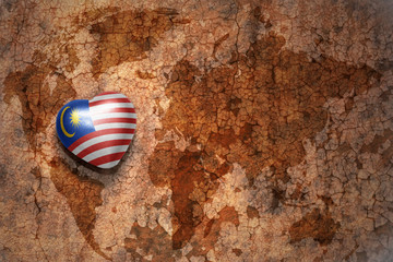heart with national flag of malaysia on a vintage world map crack paper background.