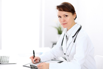 Woman doctor filling up medical history at the desk