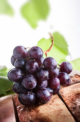 Red grapes branch wiht green leaves on old rustic wooden table