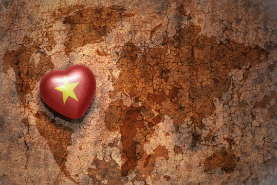 heart with national flag of vietnam on a vintage world map crack paper background.