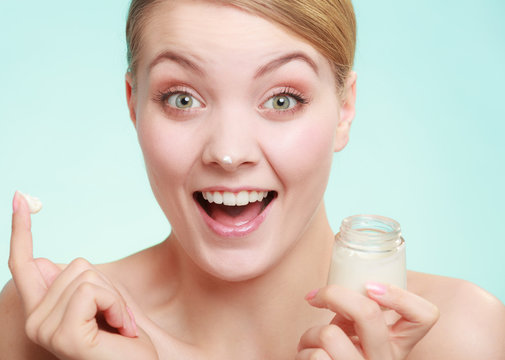 woman applying cream on her skin face.