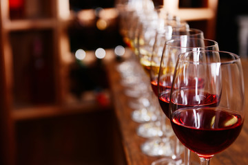 Many glasses of different wine in a row on bar counter