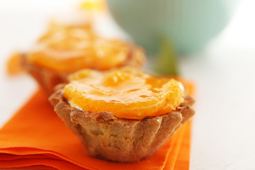 Sweet cakes with tangerines on table, close up