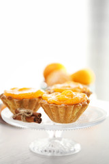 Sweet cakes with tangerines on table, close up