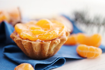 Sweet cakes with tangerines on table, close up