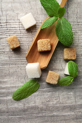Pile of brown sugar cubes and stevia  on grey wooden background