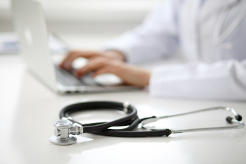 Female doctor typing on laptop, close up
