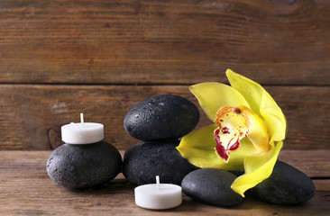 Spa still life with stones, flower and candlelight on wooden background