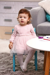 Little girl sitting on the chair in the room