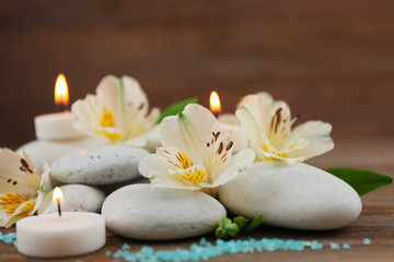 Fototapeta na wymiar Spa still life with stones, flowers and candlelight on wooden background