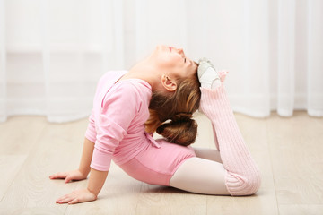 Little cute girl in pink leotard making new ballet movement at dance studio