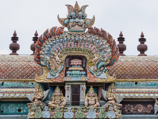 Trichy, India - October 15, 2013: Closeup of bow decoration on the Vimanam of one Gopuram at Shirangam temple. Monster face on top of bow showing small humans, elephants, horses, parrots, dogs