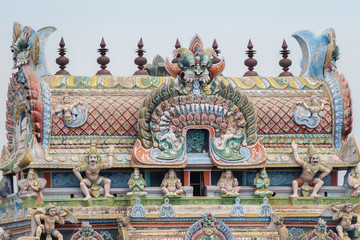 Obraz premium Trichy, India - October 15, 2013: Closeup of the top of the gopuram, called Vimanam, shaped as a cake, with plenty of statues in pastel colors. Garudas on corners.
