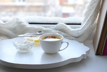 Tea set on a white wooden tray on the windowsill