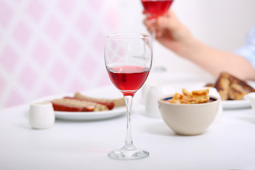 Dinner with glasses of wine on light blurred background