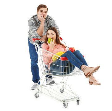 Man carrying woman in metal trolley with products isolated on white
