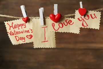 Valentine's Day card with hearts and words of love on wooden background