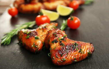 Baked chicken wings with tomatoes and rosemary on slate plate