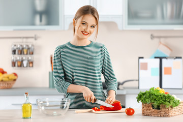 Young woman cutting vegetables for salad in the kitchen
