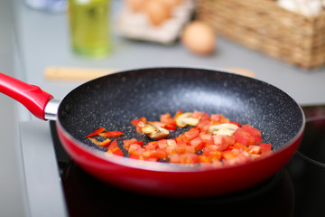 Frying pan on stove with pepper and mushrooms, closeup