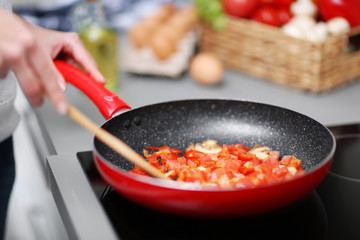 Human hands with frying pan on stove, closeup