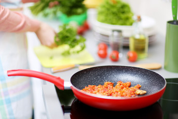 Female hands cooking on kitchen with frying pan, closeup
