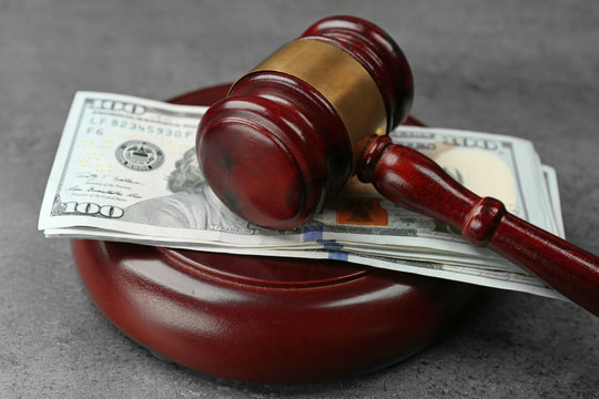Law gavel with dollars on grey background, closeup