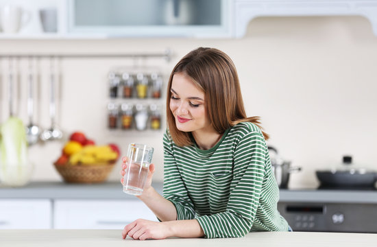 Young woman with glass of water in the kitchen