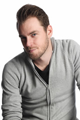 Fototapeta premium A man in his 20s wearing a grey shirt standing in front of a white background looking straight into camera.