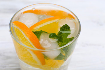 Fresh cocktail with ice, mint and orange on white wooden table background