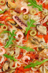 Pizza with seafood, red pepper and green olives, close up