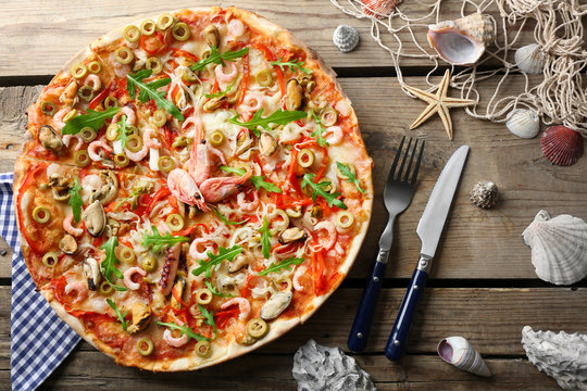 Pizza With Seafood, Red Pepper And Green Olives On Wooden Table