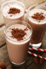 Glasses of chocolate milkshake on wooden table closeup