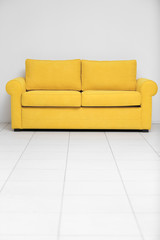 Yellow sofa on white wall background