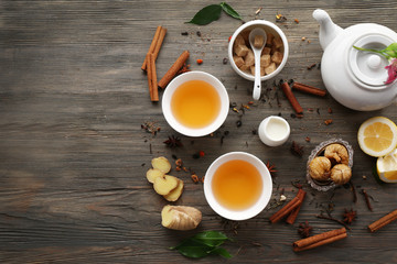 Two cups of brewed tea with ginger and spices on wooden table