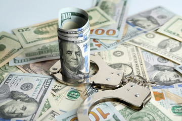 Fototapeta premium Handcuffs with rolled dollar banknote on paper background. Corruption concept