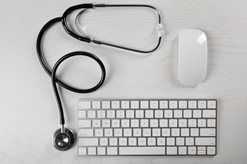 Tablet, keyboard and stethoscope on the table, top view