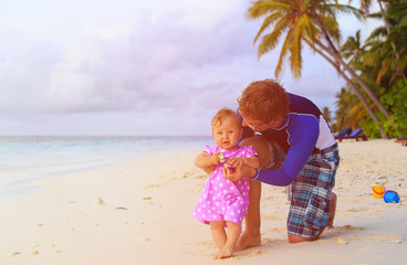 father and little daughter playing on beach