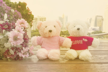 Couple teddy  bears in garden with flowers on city background ,