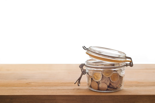 Tip Box, Coins In A Glass Jar On Wooden White Background