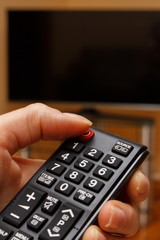 Hand holding remote control for television, choosing channel in TV