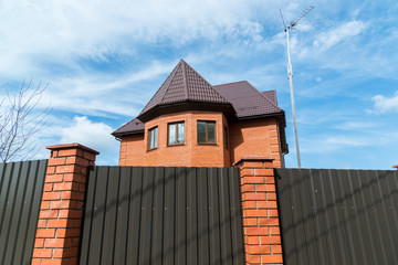Cottage from  red brick behind a high fence