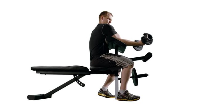 Man working out, doing bicep curls with weights on exercise bench.  Wide shot in ProRes 422HQ with clean white background, originally recorded in 12-bit 4K RAW at 24fps against green screen.