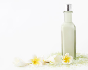 Obraz na płótnie Canvas Green cosmetic bottle with bath salt and frangipani flowers 