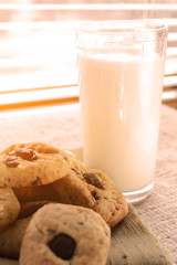 glass of milk and chocolate chip cookies at the window