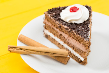 Fototapeta na wymiar Chocolate cake with cinnamon on a yellow wood table background.