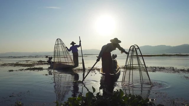 Myanmar travel attraction landmark - Traditional Burmese fishermen with fishing net at Inle lake in Myanmar famous for their distinctive one legged rowing style 4k
