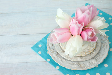 the white and pink tulips on the plate on fabric on wooden background
