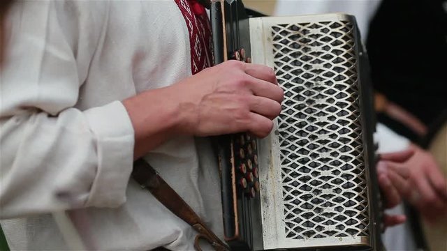 Street musicians dressed in traditional costumes play accordion drums and violin instruments outdoors 