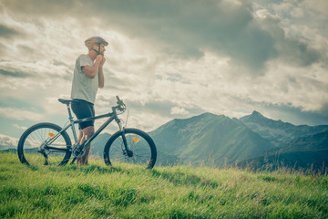 Young man stand near bike on mountain outdoor